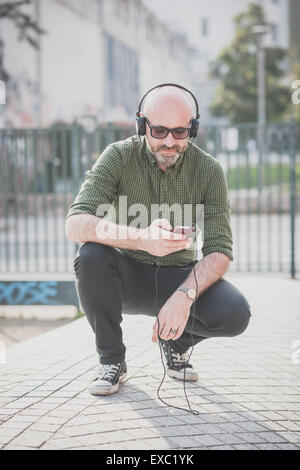 Bel uomo di mezza età ascoltando musica in città Foto Stock