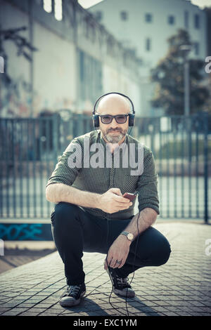 Bel uomo di mezza età ascoltando musica in città Foto Stock