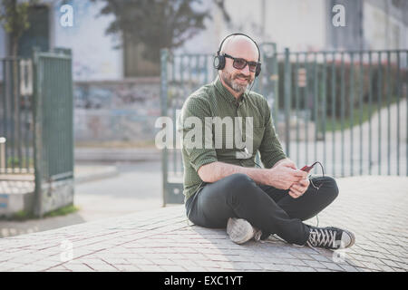 Bel uomo di mezza età ascoltando musica in città Foto Stock