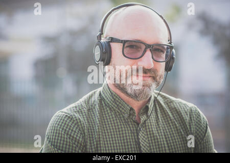 Bel uomo di mezza età ascoltando musica in città Foto Stock