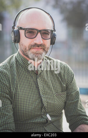 Bel uomo di mezza età ascoltando musica in città Foto Stock