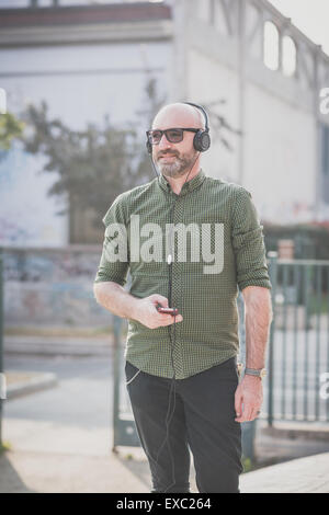 Bel uomo di mezza età ascoltando musica in città Foto Stock