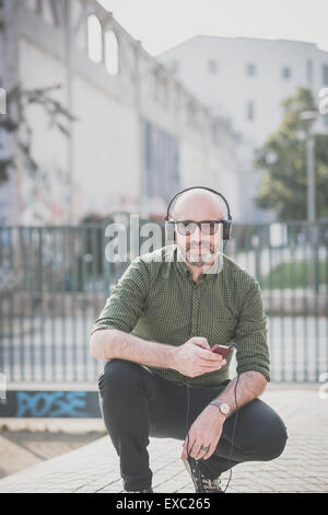 Bel uomo di mezza età ascoltando musica in città Foto Stock