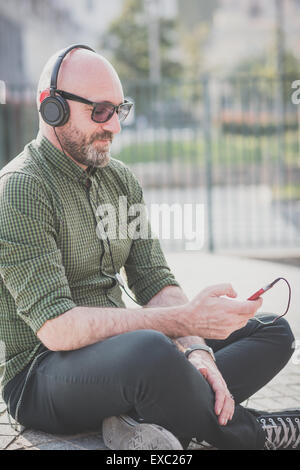 Bel uomo di mezza età ascoltando musica in città Foto Stock