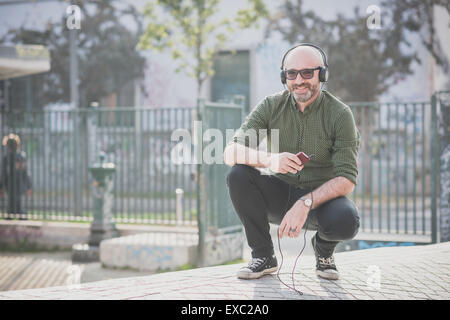 Bel uomo di mezza età ascoltando musica in città Foto Stock