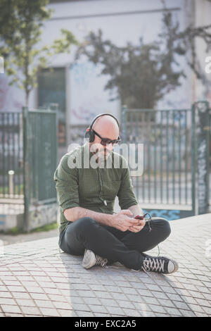 Bel uomo di mezza età ascoltando musica in città Foto Stock