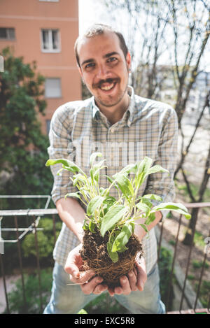 Bel uomo elegante tenuta impianto di basilico a casa Foto Stock