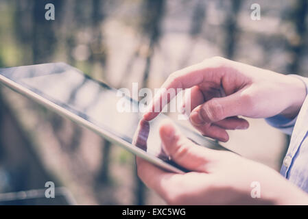 Chiudere fino a mani il multitasking uomo tablet utilizzando la connessione wifi Foto Stock