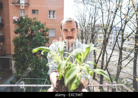 Bel uomo elegante tenuta impianto di basilico a casa Foto Stock