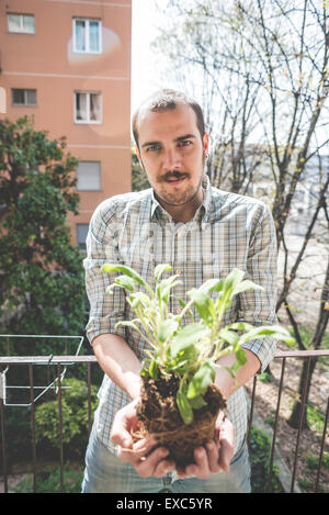 Bel uomo elegante tenuta impianto di basilico a casa Foto Stock