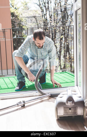 Bello elegante uomo utilizzando hoover a casa Foto Stock