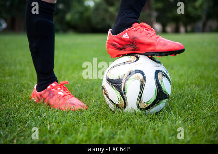 Close up di un giovane ragazzo con un piede su un campo di calcio Foto Stock