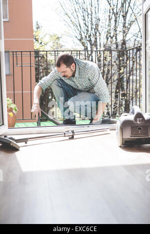 Bello elegante uomo utilizzando hoover a casa Foto Stock