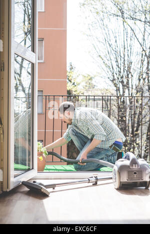 Bello elegante uomo utilizzando hoover a casa Foto Stock