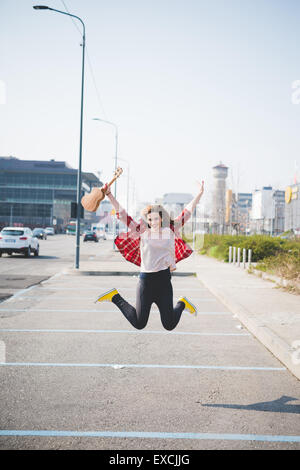 Giovane bella bionda hipster donna nella città con ukulele Foto Stock