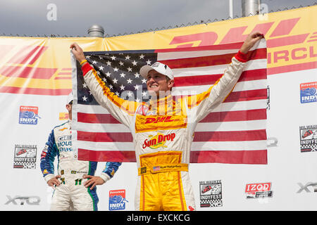 Vincitore del 2012 Indyfest, Ryan Hunter-Reay del team DHL, sorge al vincitore's circle tenendo in mano una bandiera americana. Foto Stock