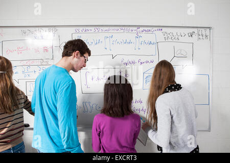 Alta scuola gli studenti lavorano su equazioni su un bianco in aula lavagna cancellabile. Foto Stock