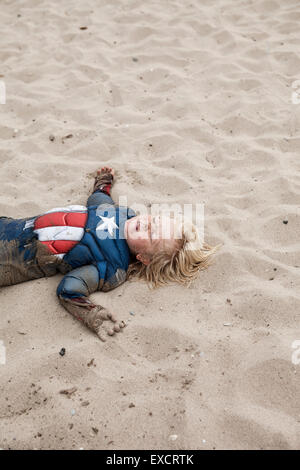 A quattro anni di vecchio ragazzo che indossa un capitano America svolge in costume su una spiaggia di sabbia sul Lago Michigan. Foto Stock