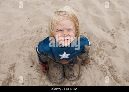 A quattro anni di vecchio ragazzo che indossa un capitano America svolge in costume su una spiaggia di sabbia sul Lago Michigan. Foto Stock