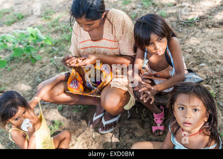 Giovani Wayuu donna e bambini seduti fuori mentre lo tesse in un 'rancheria', o tradizionale insediamento Wayuu in La Guaji Foto Stock