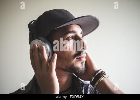 Giovane uomo elegante ascoltando musica su sfondo grigio Foto Stock