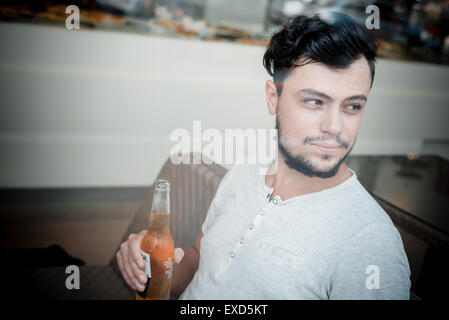 Giovane uomo elegante al bar a bere birra Foto Stock
