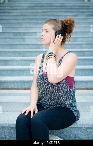 Bella elegante e moderna giovane donna ascoltando musica in città Foto Stock