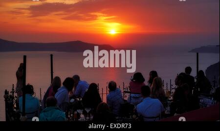 Persone bere e mangiare in un ristorante all'aperto durante il tramonto a Fira, Santorini, Grecia. Foto Stock