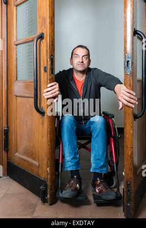 Uomo in sedia a rotelle bloccato tra le porte di oscillazione Foto Stock