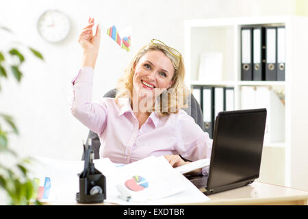 Di mezza età business donna gettando aeroplano di carta e sognare di vacanza in ufficio Foto Stock