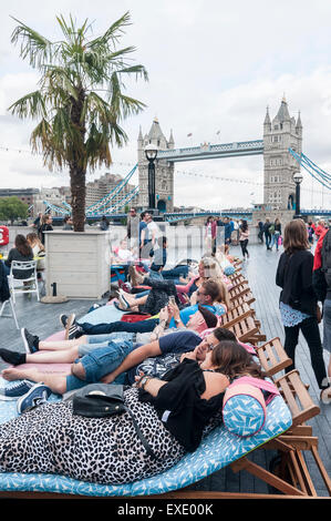 Londra, Regno Unito. 12 Luglio, 2015. Meteo REGNO UNITO: turisti approfittare delle sedie a sdraio e posti a sedere in mezzo alle palme vicino al City Hall. Credito: Stephen Chung / Alamy Live News Foto Stock