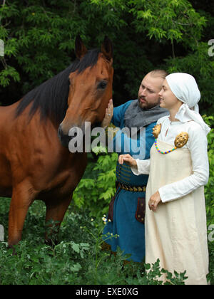 Coppia sposata vestito in abiti dei vichinghi giocando con un cavallo Foto Stock