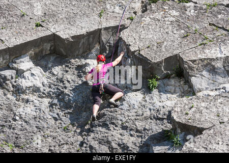 La donna fissata con funi è scalare una roccia verticale lungo il fiume Mosa vicino a Dinant, Belgio Foto Stock