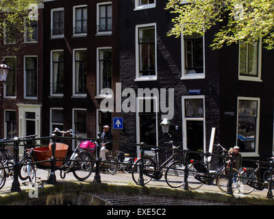 Un ciclista attraversa un ponte sul Reguliersgracht, quartiere Jordaan, Amsterdam, Paesi Bassi Foto Stock