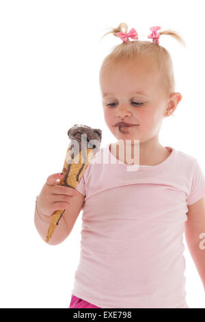 Ritratto toddler ragazza di mangiare il gelato al cioccolato isolate su sfondo bianco Foto Stock