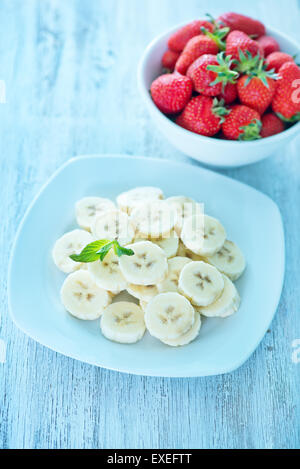 Banana con fragola sulla piastra e su una tavola Foto Stock