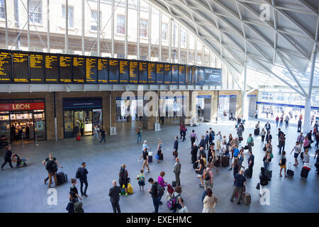 Pendolari guardando le partenze board presso la stazione ferroviaria di King's Cross - Londra, Inghilterra Foto Stock