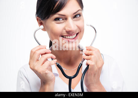 Ritratto di un giovane medico donna tenendo uno stetoscopio isolati su sfondo bianco. Guardando cmaera Foto Stock