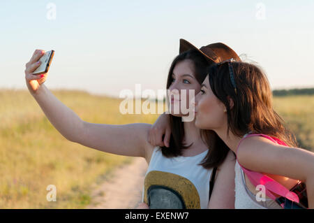 Due ragazze adolescenti tenendo selfie e divertimento all'aperto Foto Stock