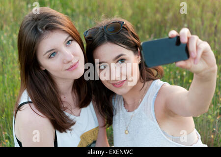 Due ragazze adolescenti tenendo selfie e divertimento all'aperto Foto Stock