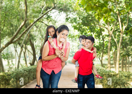 Indian i genitori con bambini park godetevi Piggyback Equitazione Foto Stock