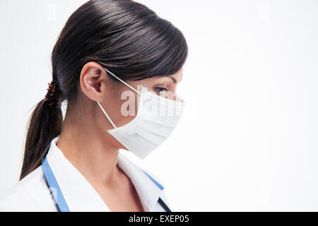 Vista laterale verticale di una femmina pensieroso medico in maschera isolata su uno sfondo bianco Foto Stock