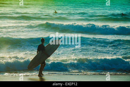 Il pilota di surf che guarda l'acqua con la fotocamera di ritorno a Palm Beach di Sydney all'alba, senza la corda per le gambe e senza la muta Foto Stock