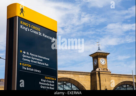 Un segnale pedonale in Kings Cross identificazione di siti locali di interesse. L'edificio principale di Kings Cross Station può essere visto in Foto Stock