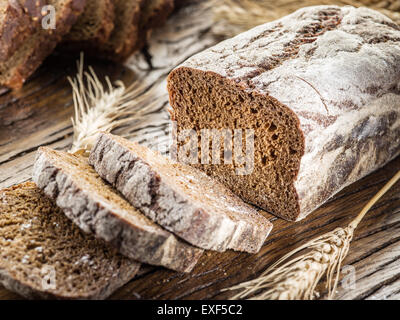 Fette di pane nero sul vecchio asse di legno. Foto Stock