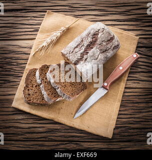 Fette di pane nero sul vecchio asse di legno. Foto Stock