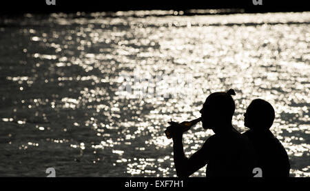 Berlino, Germania. Il 29 giugno, 2015. Due persone sedersi accanto al fiume Sprea, con uno di loro a bere birra, a Berlino, Germania, 29 giugno 2015. Foto: Florian Gaertner/dpa/Alamy Live News Foto Stock