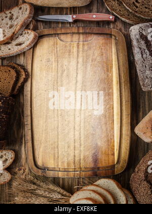 Fette di pane nero sul vecchio asse di legno. Foto Stock