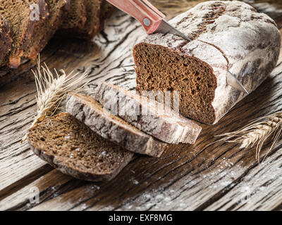 Fette di pane nero sul vecchio asse di legno. Foto Stock