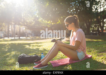 Giovane donna rivista di lettura nel parco, Manila, Filippine Foto Stock